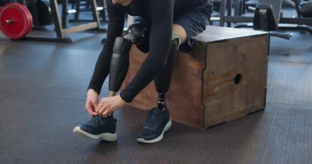 在健身房 截肢的男子运动员用现代设备把鞋带绑在健身箱上 健康与身体护理慢动作的家伙打滑鞋带 准备运动 — 图库视频影像