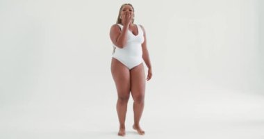 Sevecen, koyu tenli, kilolu kadın dansçı beyaz mayo giymiş beyaz arka plan vücut dili kavramına karşı hava öpücüğü gönderiyor.