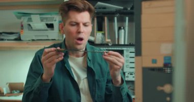 Teknisyen tamirhanedeki çipin tozunu üfleyen bilgisayar parçalarını tamir ediyor. Yavaş çekim, elektronik sistem kartını kontrol eden, pislikten temizleyen adam.