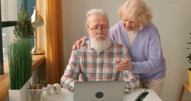 Mutlu yaşlı çift birlikte dizüstü bilgisayar kullanıyor, online alışveriş yapıyor, yaşlı emekli aile kitap okuyor internet haberlerini tartışıyor, internet sitesinden seyahat teklifini seçiyor, kadın kocasına su veriyor