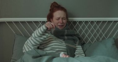 depresif, solgun bir kadın hasta yatağa uzanıp ağlıyor, başı ağrıyor, kağıt mendil tutuyor ve gözyaşlarını siliyor. Yavaş çekim Üzüntü Konsepti.