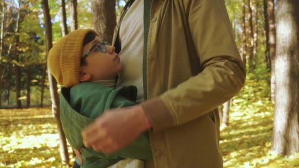 公園を歩いている間にお父さんを受け入れる暖かい服のメガネの帽子で幸せなかわいい息子 スローモーション貴重な瞬間父と若い息子の親密さ 愛の関係 — ストック動画