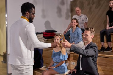 Dost canlısı Afrikalı Öğretmen Öğrenciye Kalem Veriyor, Konferans Salonunda Güzel Eğitim, Yan Görünüm. Arka plandaki bir grup öğrenci, uzayı kopyalayın. Eğitim, Öğrenim, İş, Yönetim