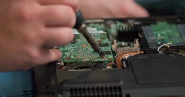 Erkek mühendis elektronik devre kartını lehimleme demiriyle onarmaya odaklanmış. İnsan askerlere bilgisayar devre kartını lehimleme demiriyle veriyor. Yavaş çekimde kırpılmış görüntüyü kapat. bilgisayar