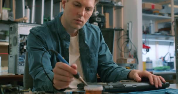 フェアヘアーフォーカシング技術者は コンピュータ回路基板の概念技術を電子的に修復するためにハンダ付け鉄を使用しています — ストック動画