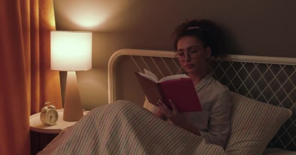 她拿着一本书正准备睡觉 她把书放在桌上 关掉灯 睡着了 近视侧视拍摄 慢动作 — 图库视频影像