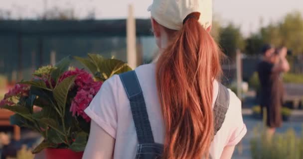Şapkalı Üniformalı Kadın Turuncu Içinde Yürüyorlar Çiçek Saksısını Yere Koyuyorlar — Stok video
