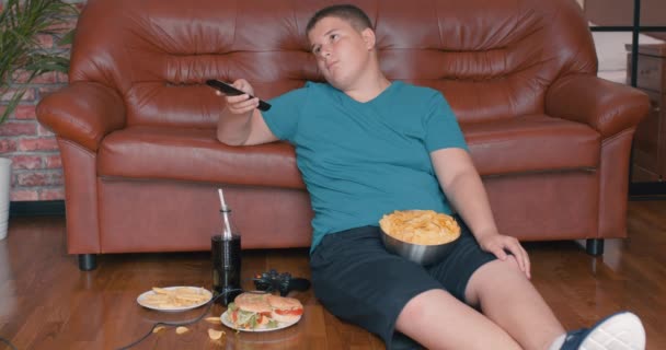 Lazy Young Boy Sitting Floor Holding Remote Control Changing Channels — Stock Video