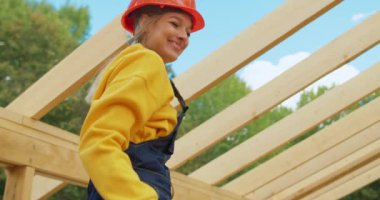 Şantiyede çalışan erkek meslektaşı, elinde matkap tutan kız bitmemiş bir yazlık evindeki kameraya bakarken, komik bir şekilde gülüyordu.