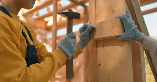 强壮的女工在木架上锤打钉子 而男人则教女人锤打 慢动作这不是女人的工作 剥削女性装修延伸木结构房屋 — 图库视频影像