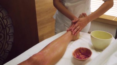 Profesyonel masör spa salonunda kadın bacaklarına pembe ovalar sürüyor. Pratisyen, selülitten kurtulmak için anti-selülit masajı yapar.