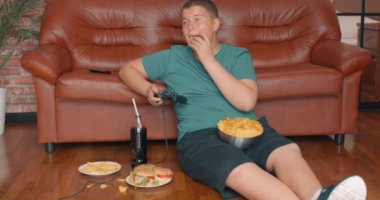 Ciddi tombul çocuk video oyunları oynamaya odaklanmış. Ağır çekim. Bağımlılık, çocuk fast food ve bilgisayar oyunlarına bağımlıdır