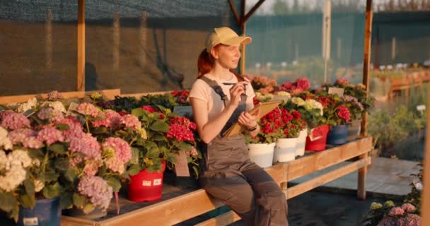 Smiling Successful Woman Gardener Writing Paper Notebook Sitting Many Flowers — Stock Video