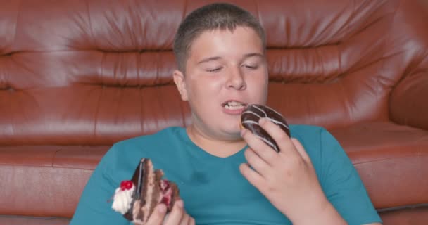 胖胖的少年不停地吃着美味的糖果 他喜欢吃蛋糕甜甜圈 男孩吃着很多含糖的食物 健康问题 — 图库视频影像