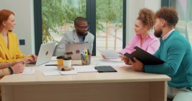 Afrikalı Amerikalı lider ve ekibi ofiste iyi eğlenceler, Ağır çekim. Çok ırklı iş arkadaşları toplantı odasında toplanıp toplantıda fikir alışverişinde bulundular..