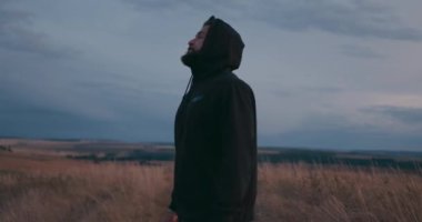 Siyah kapüşonlu yakışıklı sakallı sporcu aşırı egzersizden sonra yavaş çekim fitness ve sağlıklı yaşam tarzı konsepti, koşucu akşamları dışarıda dinleniyor, yakından bak.