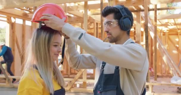 Erkek Kız Arkadaşına Şapkasını Takıyor Müstakbel Evlerini Inşaatta Eğlenirken Gösteriyor — Stok video