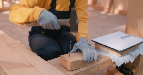 若い女性大工の制服や手袋ハンマー釘を学ぶ スローモーション女性は 木材を爪するハンマーを使用しています — ストック動画