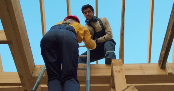 Erkek Müteahhit Dişinin Merdivendeki Ahşap Binanın Çatısına Tırmanmasına Yardım Ediyor — Stok video