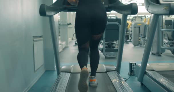 Kvinna Sportkläder Med Muskulösa Ben Går Löpband Tillbaka Sällsynt Visa — Stockvideo