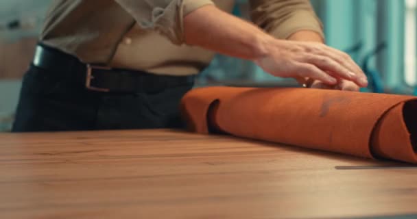 手工艺者打开桌子上的卷材 缝制加工前将其平整慢动作车间用于特殊定单皮革制品 制造业和鞋类生产流程 — 图库视频影像