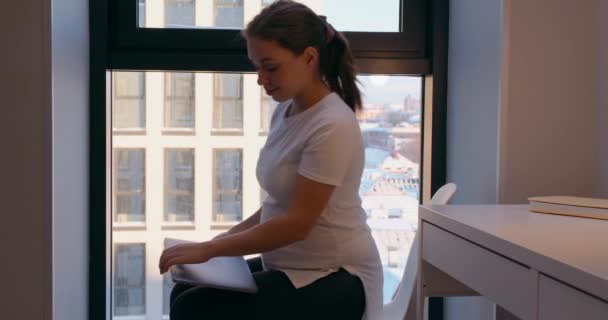 怀孕妇女使用笔记本电脑 在卧室的椅子上休息 快乐的微笑的女孩享受怀孕的快乐慢动作 — 图库视频影像