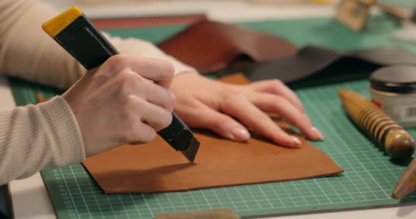 女皮革手工制造的服装裁剪手正在使用一把刀具 根据设计裁剪一块橙色皮革大片 为客户带来缝制产品 速度较慢 — 图库视频影像