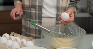 Kafkas kadın şefin elleri cam kâseye yumurta kırıyor mutfak masasında omlet pişiriyor. Yaşam tarzı sağlıklı yeme ve geleneksel fırın konsepti. Yakın çekim kırpılmış atış