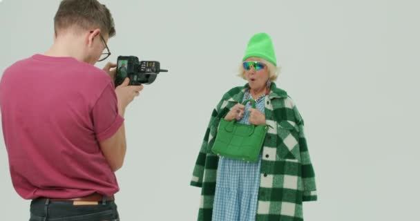 남자는 선글라스 할머니 작가에 슬로우 배경에서 매력적인 여자의 사진을 — 비디오