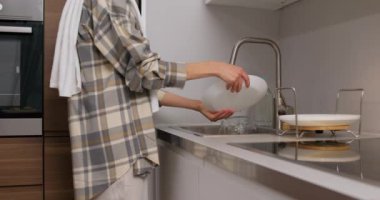 Genç bir kadın omzunda havluyla lavaboya gidiyor, kirli tabakları, tabakları, bardakları, kadehleri, yavaş çekim odak noktasını kapatıyor.