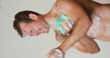 Mutlu fitness yakışıklı adam sabah duş alıyor. Vücut geliştiren kaslı sporcu eğitimden sonra duş alıyor. Banyoda yıkanan seksi adam. Çıplak adam köpükle duş alıyor. Yavaş çekim dikey bakış açısı.