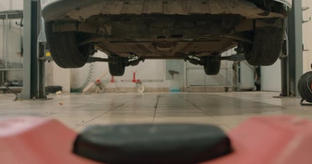 汽车的底部 相机的运动 对小型卡车和小轿车进行维修 修理和检查 慢动作 空车库 — 图库视频影像
