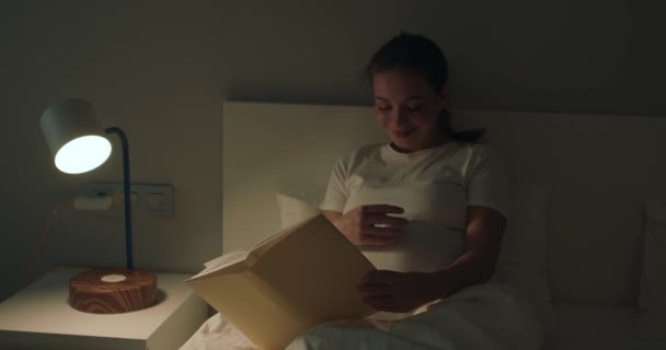 幸せな笑顔の妊婦 ベッドに行く前に本を読んで スローモーション 本を閉じる女性 眠っているライフスタイル レジャー — ストック動画