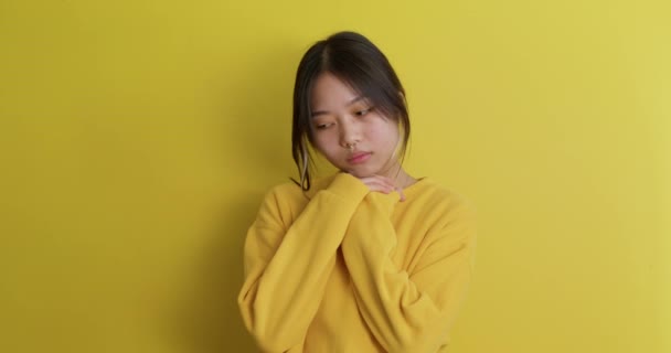 演播室里描绘不快乐的沮丧的年轻韩国人 中国女人感到孤独孤独 孤独的黄背景慢动作 女孩单独抱着自己 出现了忧郁症症状 — 图库视频影像