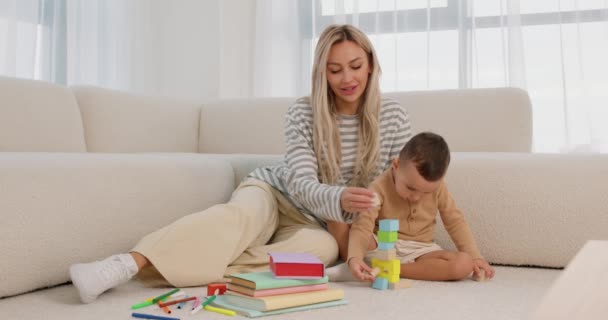 Lächelnde Kaukasische Frau Spielt Mit Kleinem Sohn Auf Warmem Boden — Stockvideo
