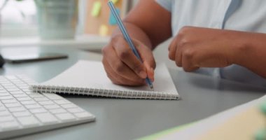 Beyaz gömlekli Afro-Amerikalı bir kadın dizüstü bilgisayarının yanına yavaş çekim eğitim alan bir not defterine yazıyor. Ofis evrakları. İş kontrol listesi. Kadın kadın elleri iş kurumsal görevleri yazıyor