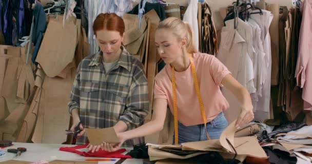 2人のアクティブなテールデザイナーが繊維工場で働き 生地を選び パテントし 女性の労働者は織物工場のチームワークの刺繍の準備ができているいくつかの衣服を得ます — ストック動画
