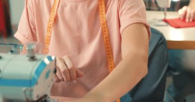 Moda giysiler, kıyafetler yaratma süreci. Çekici genç bayan terzi stüdyo kızında dikiş makinesine oturur ve dikiş diker. Yeni başlayanlar için dikiş dikme teknikleri öğrenir.