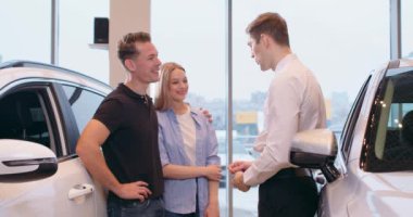 Satıcı araba galerisindeki kadın ve erkek müşterilere el sıkışırken tezgahtar yeni aracın anahtarlarını mutlu aileye veriyor, hayaller gerçek oluyor. Piyangodan uzun zamandır beklenen satın alma hediyesi