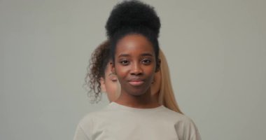 Çok ırklı kızlar, kameraya gülümseyen, yaşam tarzı konseptine gülümseyen Afrikalı Amerikalı kadınların arkasında duruyor. Komik kadınlar stüdyo danslarında eğleniyor, dansçılar dans etmeye hazırlanıyor.