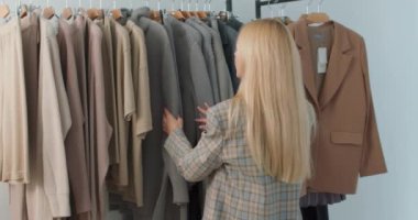 Kişisel stilisti mağazadan elbise seçiyor. Güzel moda stilisti bayan müşterisi için kıyafet seçiyor. Alışveriş merkezinde alışveriş yapan kız Yavaş çekim dükkânı asistanı müşterilerin şık görünmesine yardımcı oluyor.