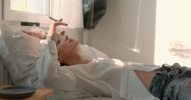 Stresli adam yatakta sigara içiyor, kötü alışkanlıklarına bakıyor. Sorunları olan yalnız bir adam. Umutsuzluk. Ağır çekim. Ateş riskini arttırıyor. Yatakta sigara içme. Tütün reklam kampanyası konsepti