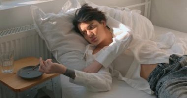 Uykulu iş adamı işini kaybetti. Adam ağzında sigara tutuyor ve yatak odasında yatağa uzanıyor. Yavaş çekim hatası Depresyon kötü şans