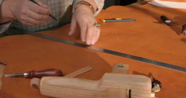 手作りの革ベルトを作る成熟した男 革の労働者は彼の研修会でベルトを作るための革のストリップを測定します スローモーション — ストック動画