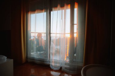 Bir odanın içinde. Gün batımında perdeli pencere 