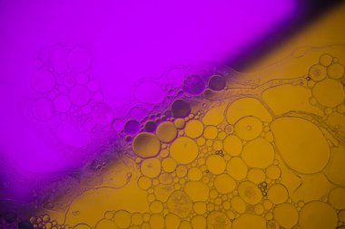 Sıvıdaki yağ kabarcıklarının üst görüntüsü. Yağ yüzeyi çok renkli arka plan. Renkli kabarcıklardan oluşan fantastik bir yapı. Suda yüzen yağ damlasının renkli sanatsal görüntüsü