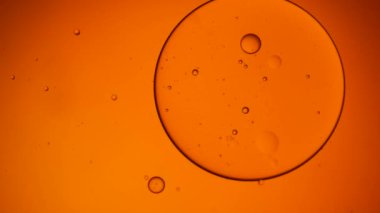 Suda yüzen yağ damlasının altın sanatçısı. Arkaplan için pastel renk balonu. Petrol damlasının turuncu arkaplanı.