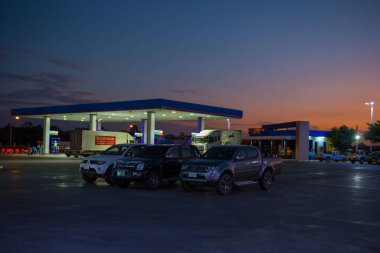 Mahasakham, Tayland - 30 Kasım 2021: PTT benzin istasyonu ve gün batımında yakıt ikmali yapılan araçlar