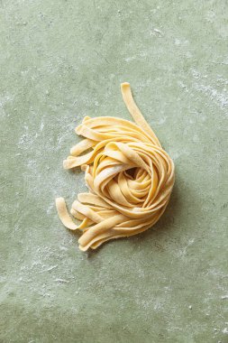 Fırınlanmamış taze çiğ ev yapımı makarna tagliatelle un kaplı bir iş yüzeyinde. 