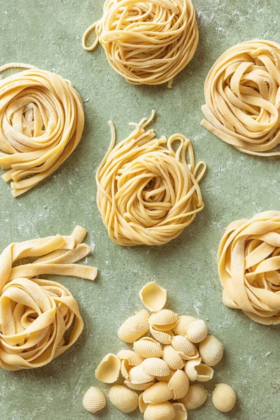 新鲜生鲜生鲜的自制面食的多样性 意大利面 意大利面和加了面粉的工作表面上的壳面食 图库图片